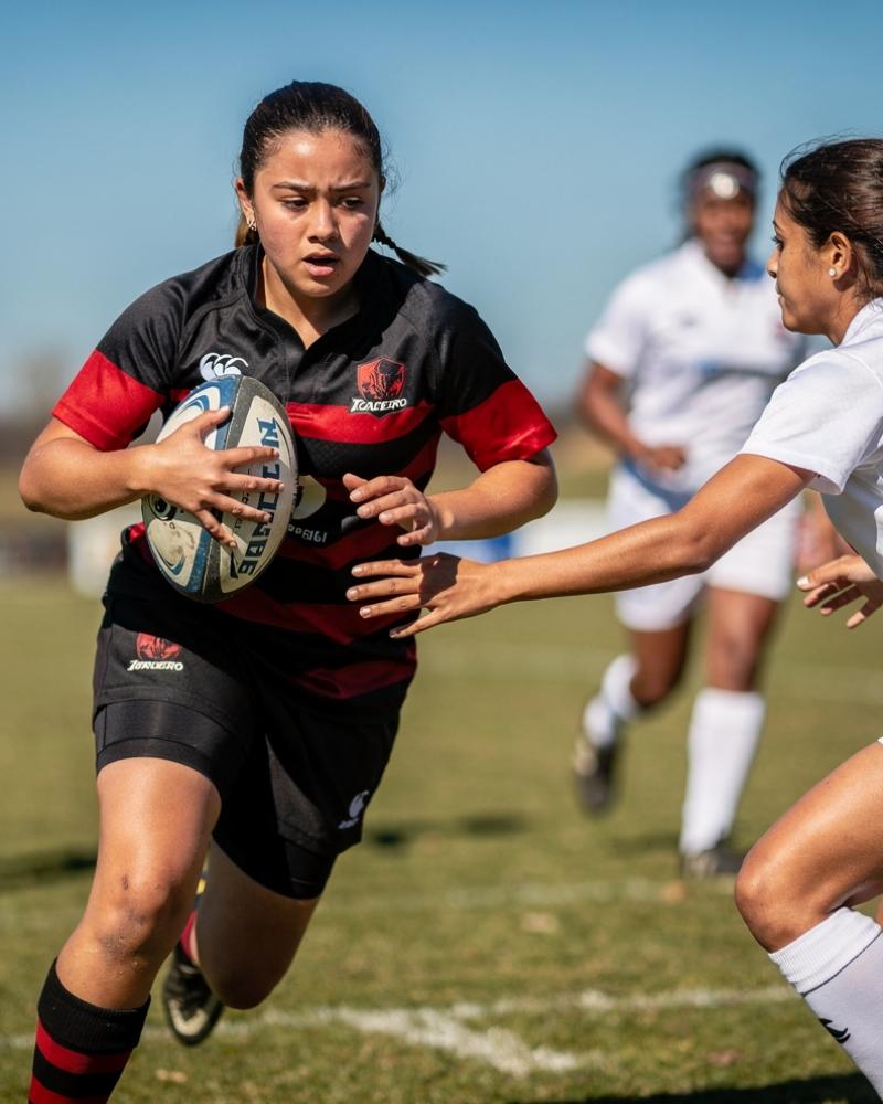 A 15-year-old girls rugby player running with the ball looking directly at the camera